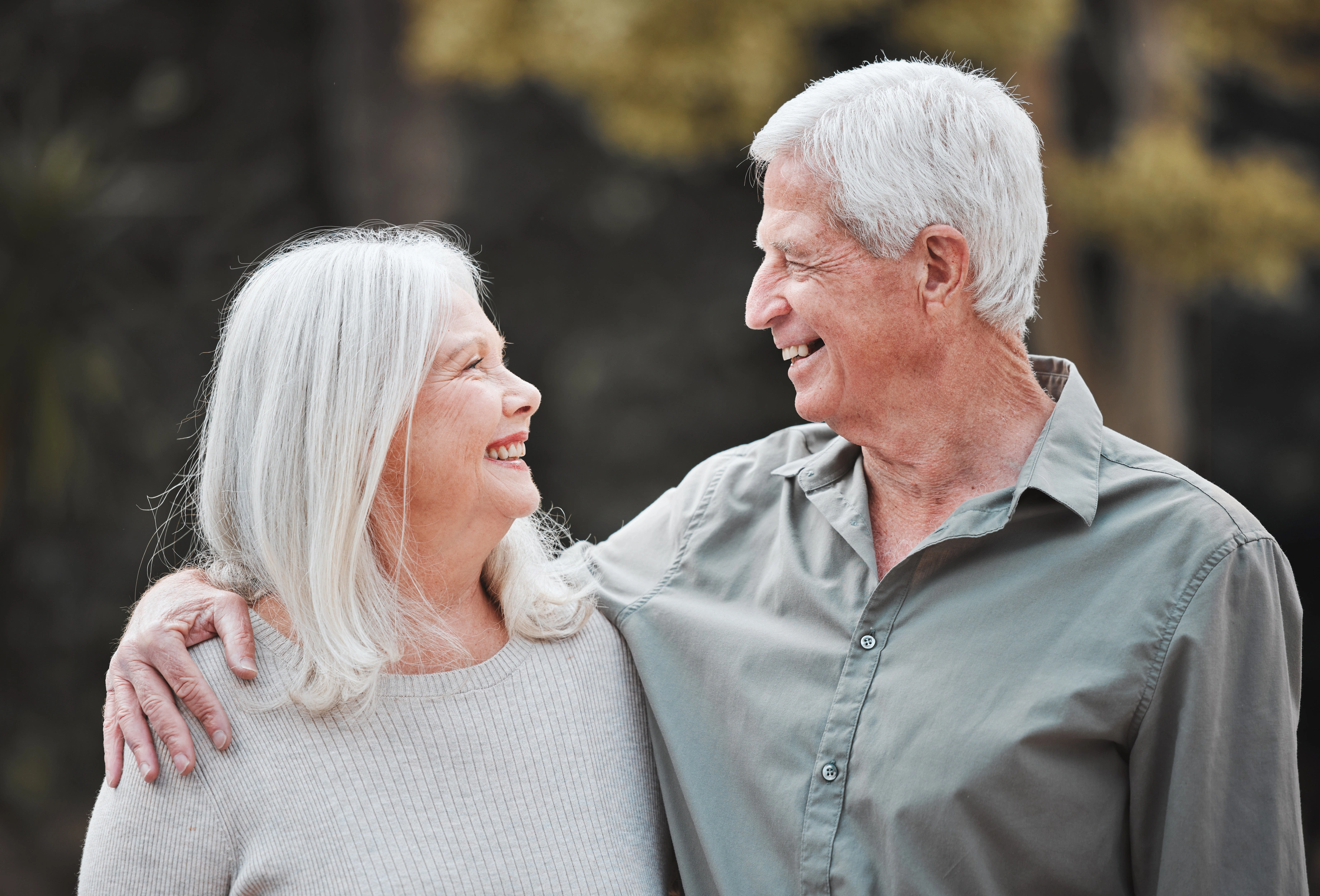 Older adult smiling outdoors while using a phone